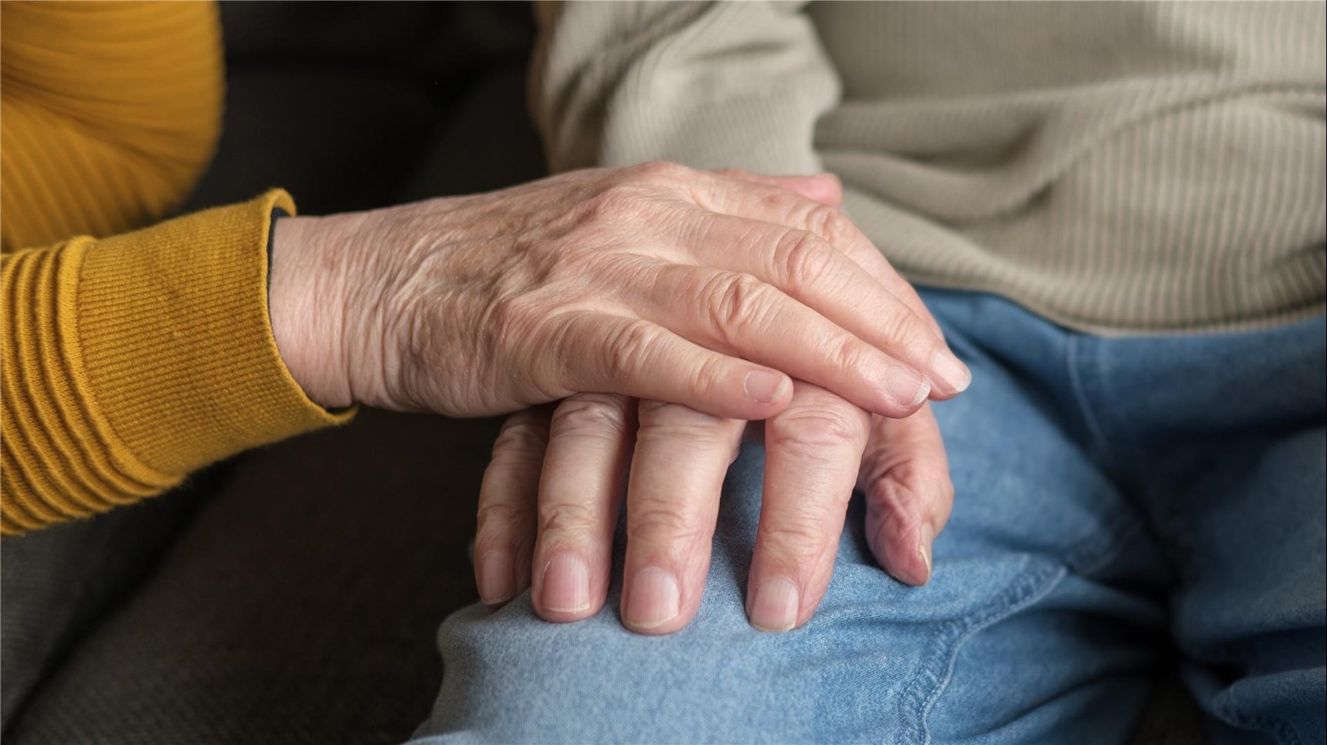 Zwei alt gewordene Hände: Eine Hand legt sich auf die Andere. 